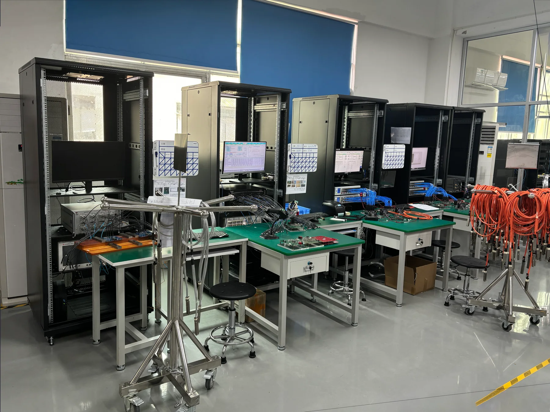 Validation benches with boards under test on ESD mats, instrument racks behind and screens showing measurement results